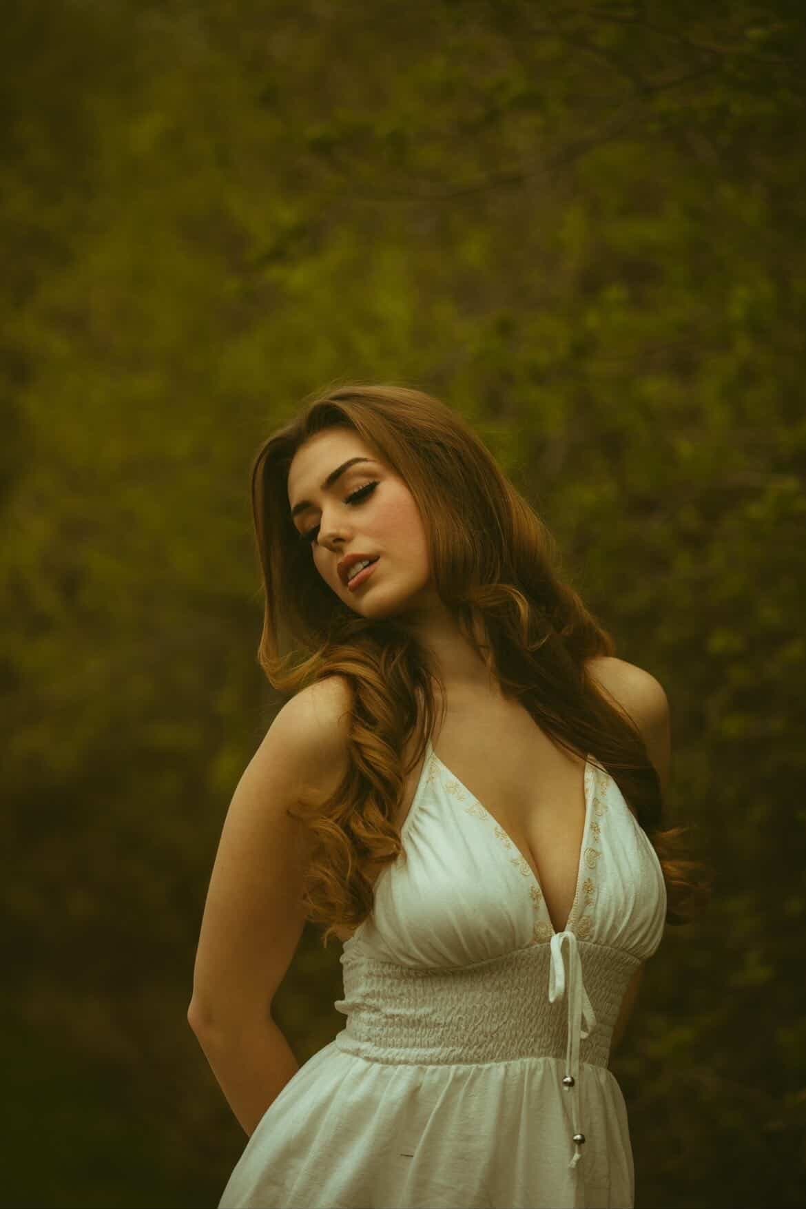 Elena standing in a white dress among spring trees