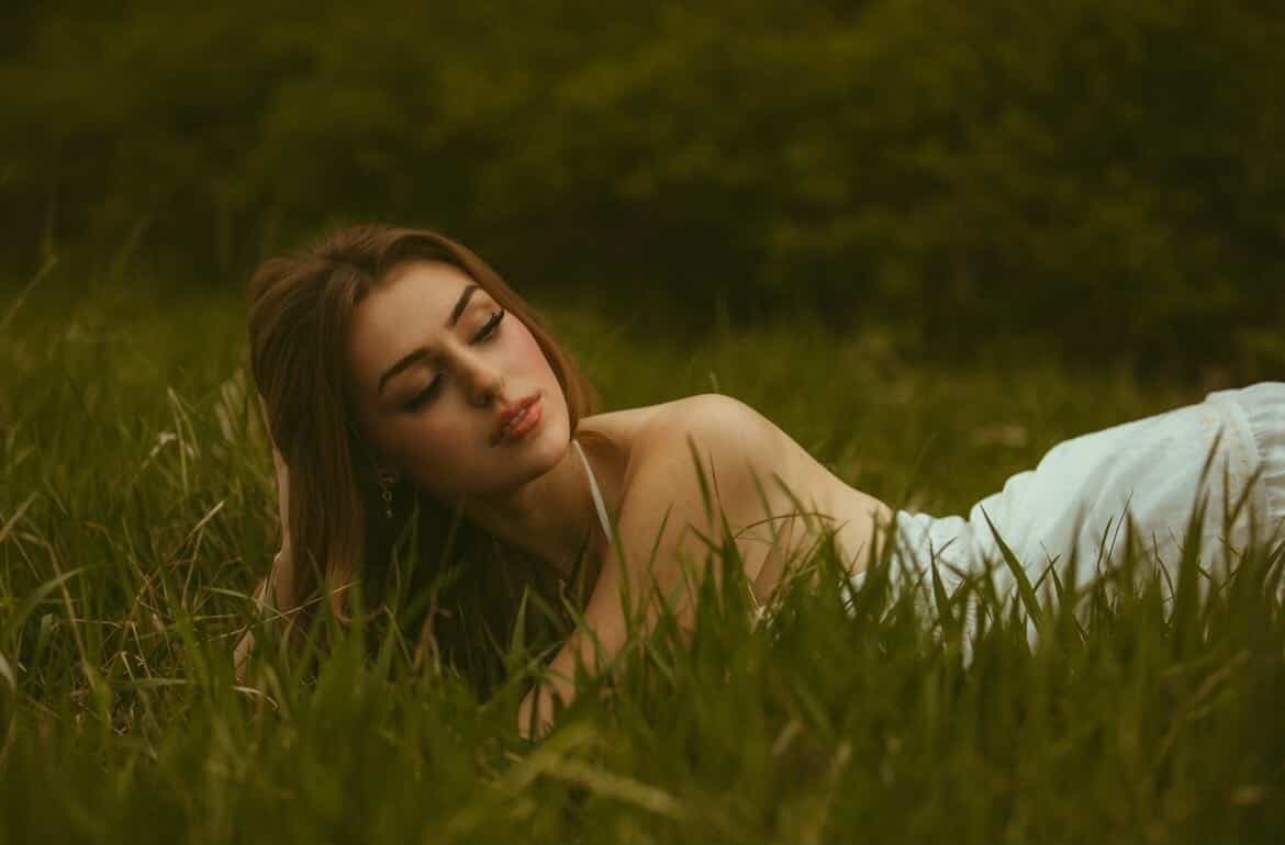 Elena lying in the meadow grass with her eyes closed